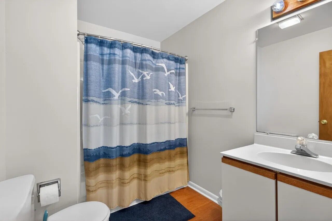 Une salle de bain avec un rideau de douche, un lavabo et un miroir.