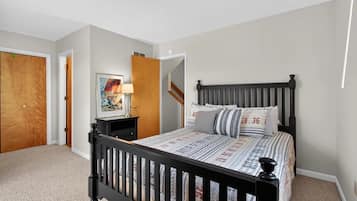 A bedroom with a bed, a nightstand, a lamp, and a door.