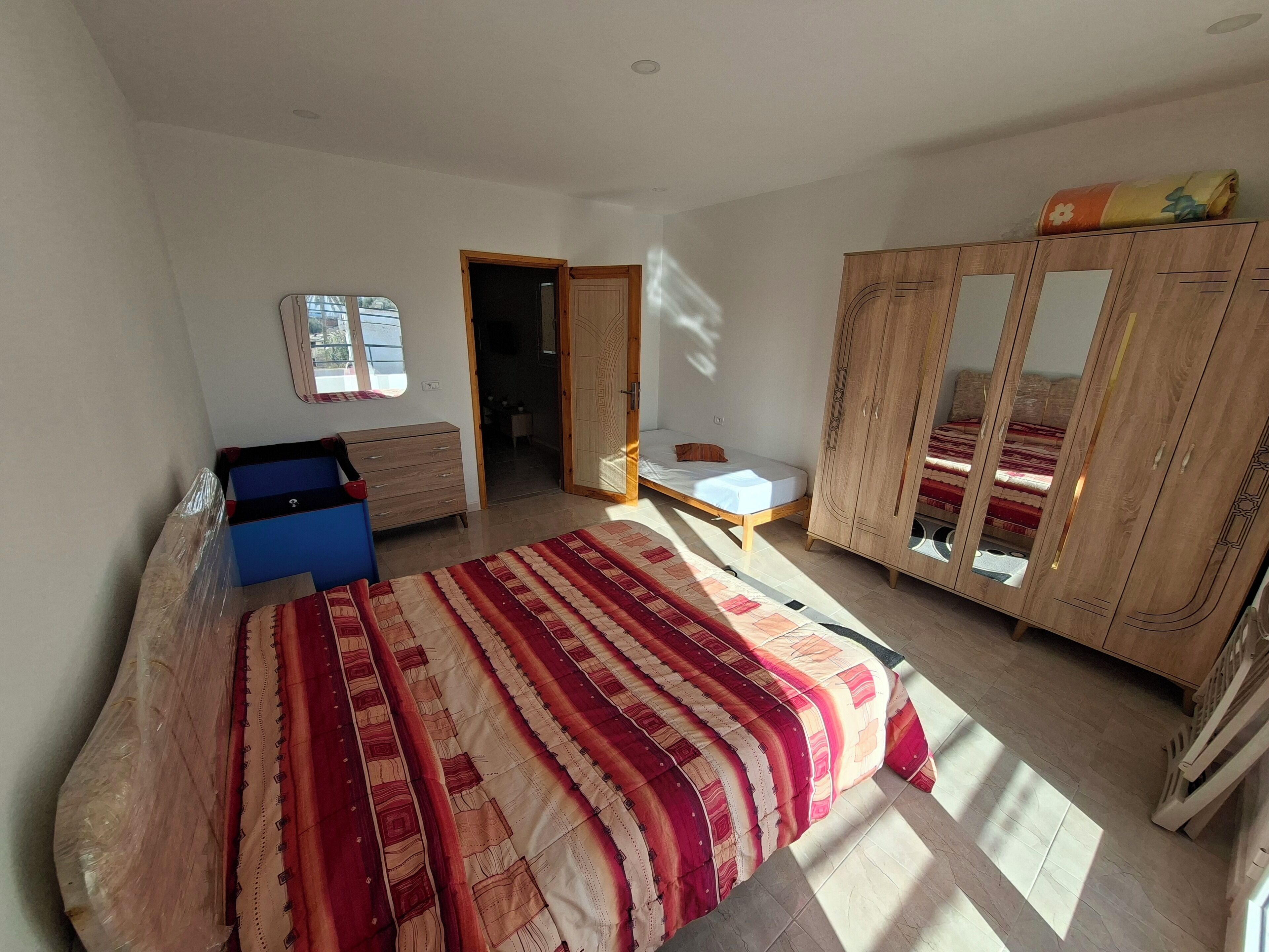 A bedroom with a bed, a wardrobe, a desk, and a window.
