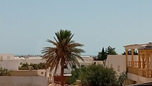 Ett bostadsområde med vita byggnader, en palm och utsikt över havet.