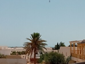 Un quartier résidentiel avec des bâtiments blancs, un palmier et une vue sur la mer.