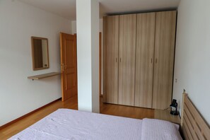 Ein Schlafzimmer mit Bett, Kleiderschrank, Spiegel und Ablagefläche.