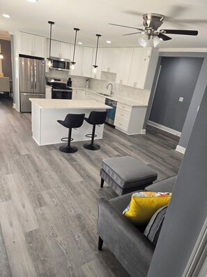 A modern kitchen with a central island, bar stools, a built-in oven, and a ceiling fan. - Amazing 4bedroom house with AC in  East Point New furn/app near airport/Stadium (East Point)