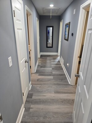 A hallway with grey walls, white doors, and a wooden floor. - Amazing 4bedroom house with AC in  East Point New furn/app near airport/Stadium (East Point)