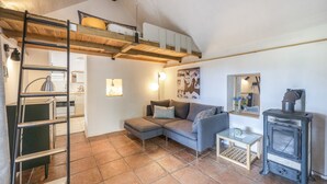 Una sala de estar acogedora con un altillo, un sofá, una mesita y un estufa de leña.