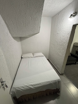 A small, narrow room with a single bed, white walls, and a textured ceiling. - Furnished Apartment in Vila Amália, North Zone (São Paulo)