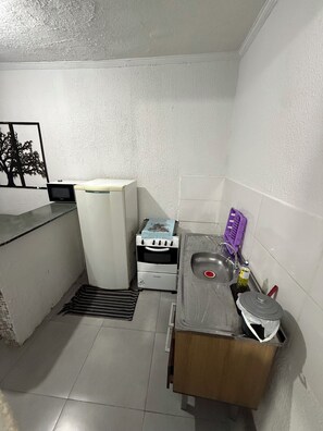 Una cocina compacta con refrigerador, horno, pileta y microondas.