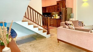 Ein großzügiger Wohnbereich mit einer Treppe, die zu einer Küche führt, einem Sofa und einem Holzkabinett.