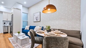 A modern living room with a dining area, a sofa, and a kitchen in the background. - The Gerrard Brand New CN Tower Home Base (Toronto)