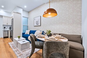 A modern living room with a dining area, a sofa, and a kitchen in the background. - The Gerrard Brand New Fifa Event Stay (Toronto)