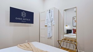 A hotel room with a bed, a robe hanging on a door, a mirror, and a sign with the hotel's name. - The Gerrard Brand New CN Tower Home Base (Toronto)
