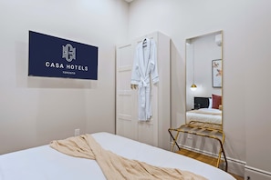 A hotel room with a bed, a robe hanging on a door, a mirror, and a sign with the hotel's name. - The Gerrard Brand New Fifa Event Stay (Toronto)