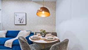 A dining area with a round table set for four, a blue sofa, and a hanging pendant light. - The Gerrard Brand New CN Tower Home Base (Toronto)