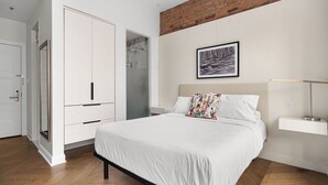 Ein Schlafzimmer mit Bett, Schrank, Dusche, einem gerahmten Bild an der Wand und einem Nachttisch.