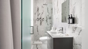 A modern bathroom with a marble wall, a shower, a toilet, and a sink with a mirror above it. - Bowery Lofts Hotel Vieux Montreal (Montréal)