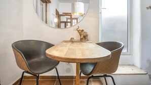 Zona pranzo con tavolo rotondo in legno, due sedie nere, uno specchio e una statuetta di elefante decorativa.