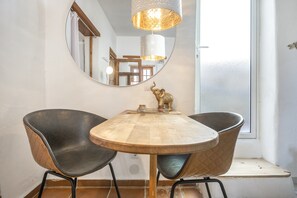 Un comedor con una mesa redonda de madera, dos sillas negras, un espejo y una figurita decorativa de elefante.