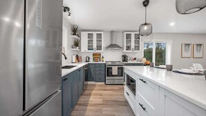 A modern kitchen with stainless steel appliances, white cabinetry, and a central island. - Pôr do Sol  Whitelake Waterfront  Group  Getaway (White Lake)