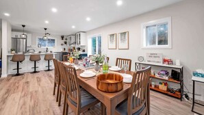 A modern kitchen with white cabinets, a dining table set for four, and a bar area with stools. - Pôr do Sol  Whitelake Waterfront  Group  Getaway (White Lake)