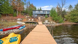 A wooden dock leading to a house by a river, with canoes and kayaks docked nearby. - Pôr do Sol  Whitelake Waterfront  Group  Getaway (White Lake)