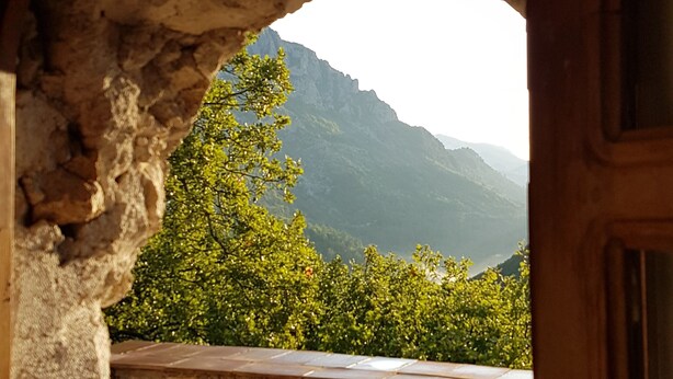 An arched stone doorway leading to a balcony with a stone wall and a view of green trees and mountains. - Nature refuge in the Estéron valley, small authentic sheepfold, bohemian spirit (Sigale)