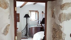 A narrow hallway leading to a bedroom with a large bathtub, a wooden door frame, and a tiled floor. - Nature refuge in the Estéron valley, small authentic sheepfold, bohemian spirit (Sigale)