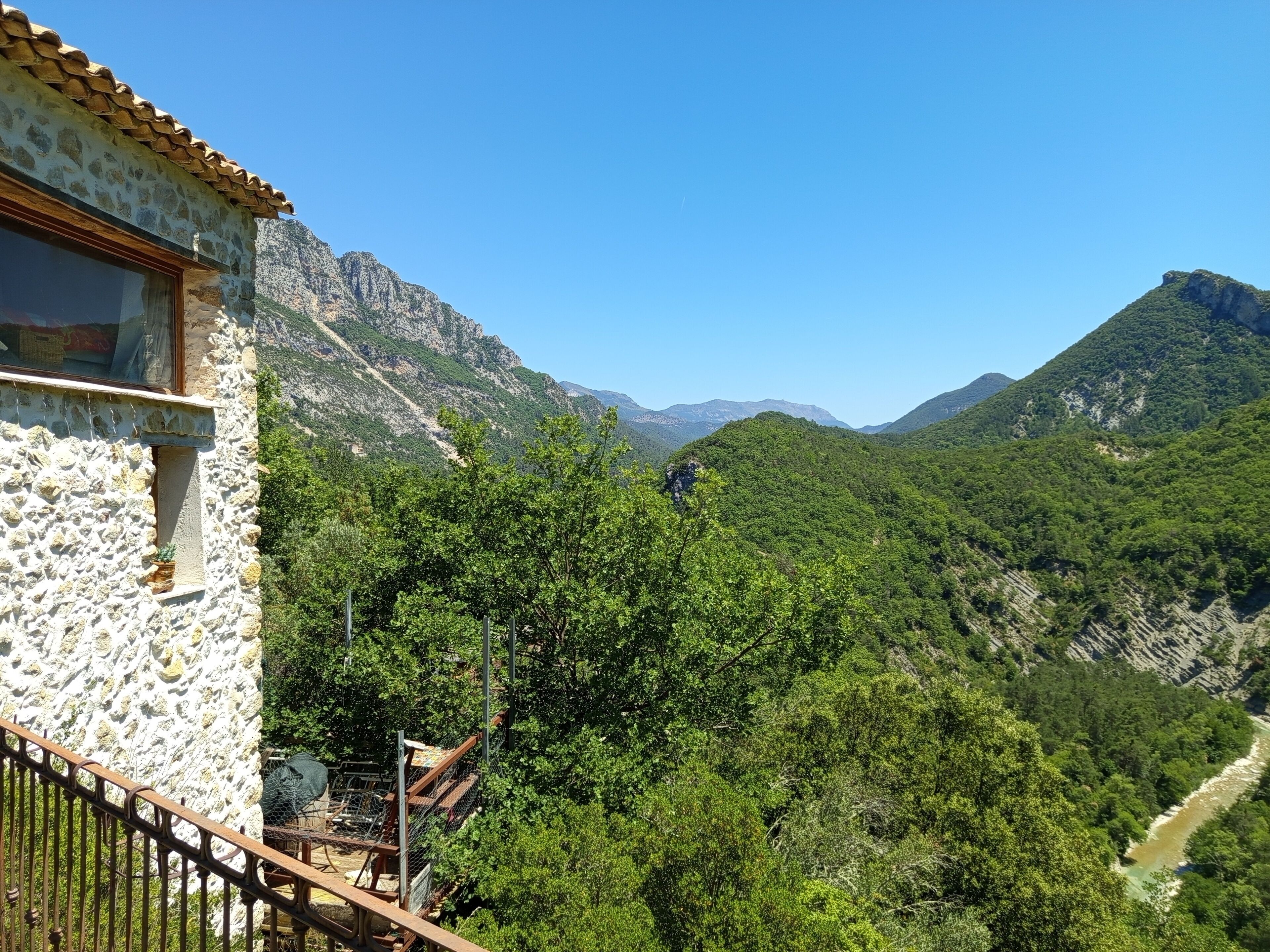 A stone building with a balcony overlooking a mountainous landscape.