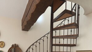 A spiral staircase with wooden steps and metal balusters, a vintage mirror, and a cabinet with drawers and a framed picture. - Nature refuge in the Estéron valley, small authentic sheepfold, bohemian spirit (Sigale)