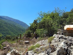 A mountainous landscape with a rustic outdoor seating area, including metal chairs and tables, surrounded by natural vegetation and a wooden structure. - Nature refuge in the Estéron valley, small authentic sheepfold, bohemian spirit (Sigale)