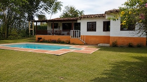 Une maison avec une piscine, une véranda et un jardin.