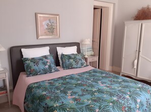 Quarto com cama, mesa de cabeceira, armário e um quadro na parede.