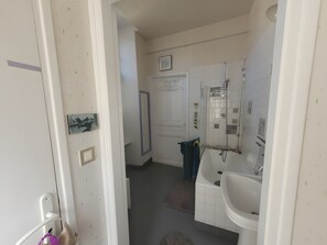 Uma casa de banho com chuveiro, lavatório e espelho.