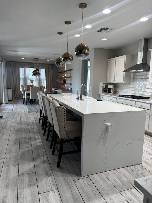 A modern kitchen with a central island, bar stools, pendant lighting, and a view to the dining area. - Spacious 4 bedroom 4 bath Retreat with Beautiful Pool in Glendale. Sleeps 10-12 (Glendale)