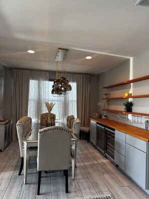 A dining area with a glass table, upholstered chairs, and a pendant light. - Spacious 4 bedroom Retreat with Beautiful Pool in Glendale. Sleeps 10-12 (Glendale)