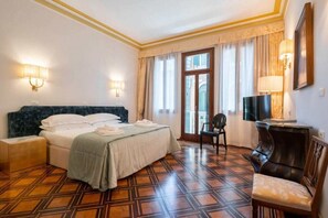 Een hotelkamer met een bed, een stoel, een televisie en een bureau.