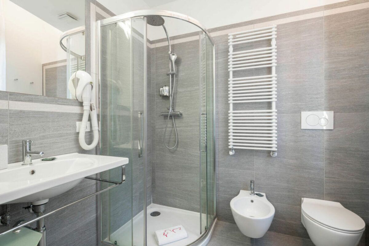 Un bagno moderno con doccia vetrata, un bidet, un WC e un lavabo con portasciugamani.