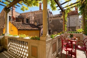Un patio con una mesa y sillas, una pérgola y un edificio con techo de tejas.