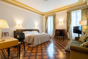 Una habitación de hotel con cama, escritorio, silla, sofá y televisor.