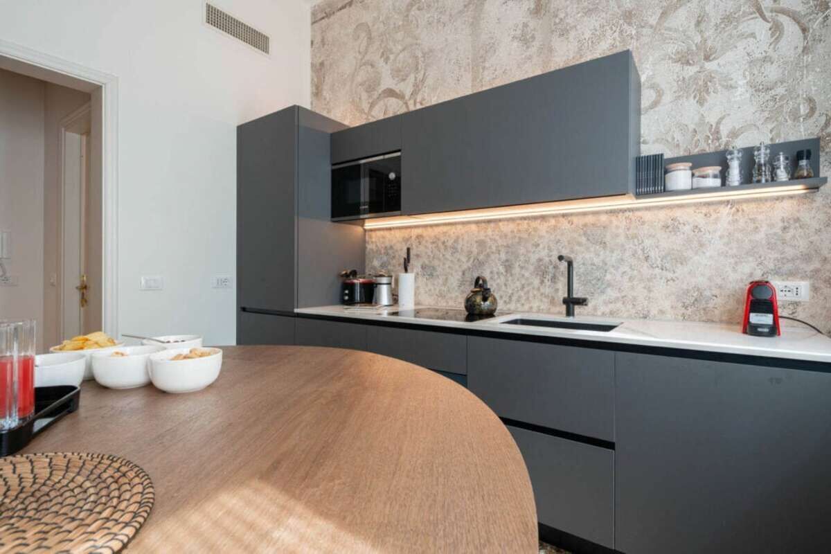 A modern kitchen with a built-in microwave, a sink, and a countertop with various items.