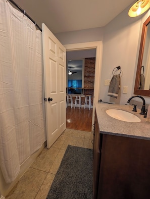 A bathroom with a sink, mirror, and shower curtain.