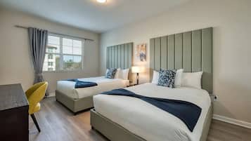 Habitación de hotel con dos camas, un escritorio y una silla.