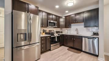 Una cocina moderna con electrodomésticos de acero inoxidable, armarios de madera oscura y piso de madera clara.