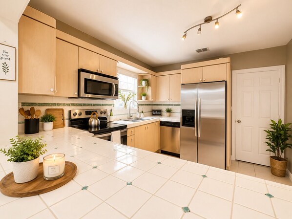 A modern kitchen with stainless steel appliances, a central island, and a welcoming sign.