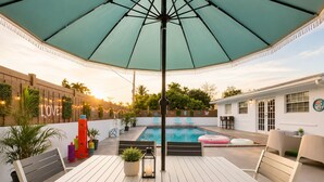 Uma área junto à piscina com mesa e cadeiras, piscina e um espaço de estar coberto.