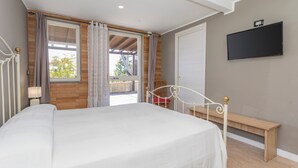 A bedroom with a bed, a bench, a TV, and a window with curtains. - Apartment in Villa with Pool (Giarre)