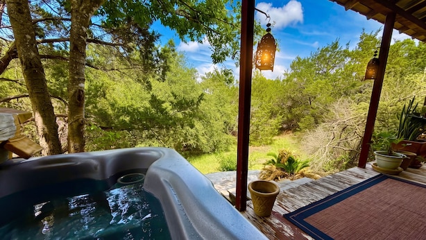 Un jacuzzi con terraza de madera, rodeado de árboles y un cielo despejado.