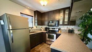 Una cocina equipada con refrigerador, estufa, microondas y pileta.