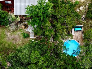 Eine Vogelperspektive auf einen Garten mit Schwimmbad, Holzpforte und üppiger Bepflanzung.
