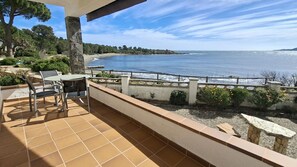 Eine Terrasse mit Tisch und Stühlen mit Blick auf einen Strand und das Meer.