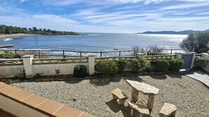 Blick auf die Küste mit einer Steinsitzbank und einem Geländer, das auf das Meer blickt.